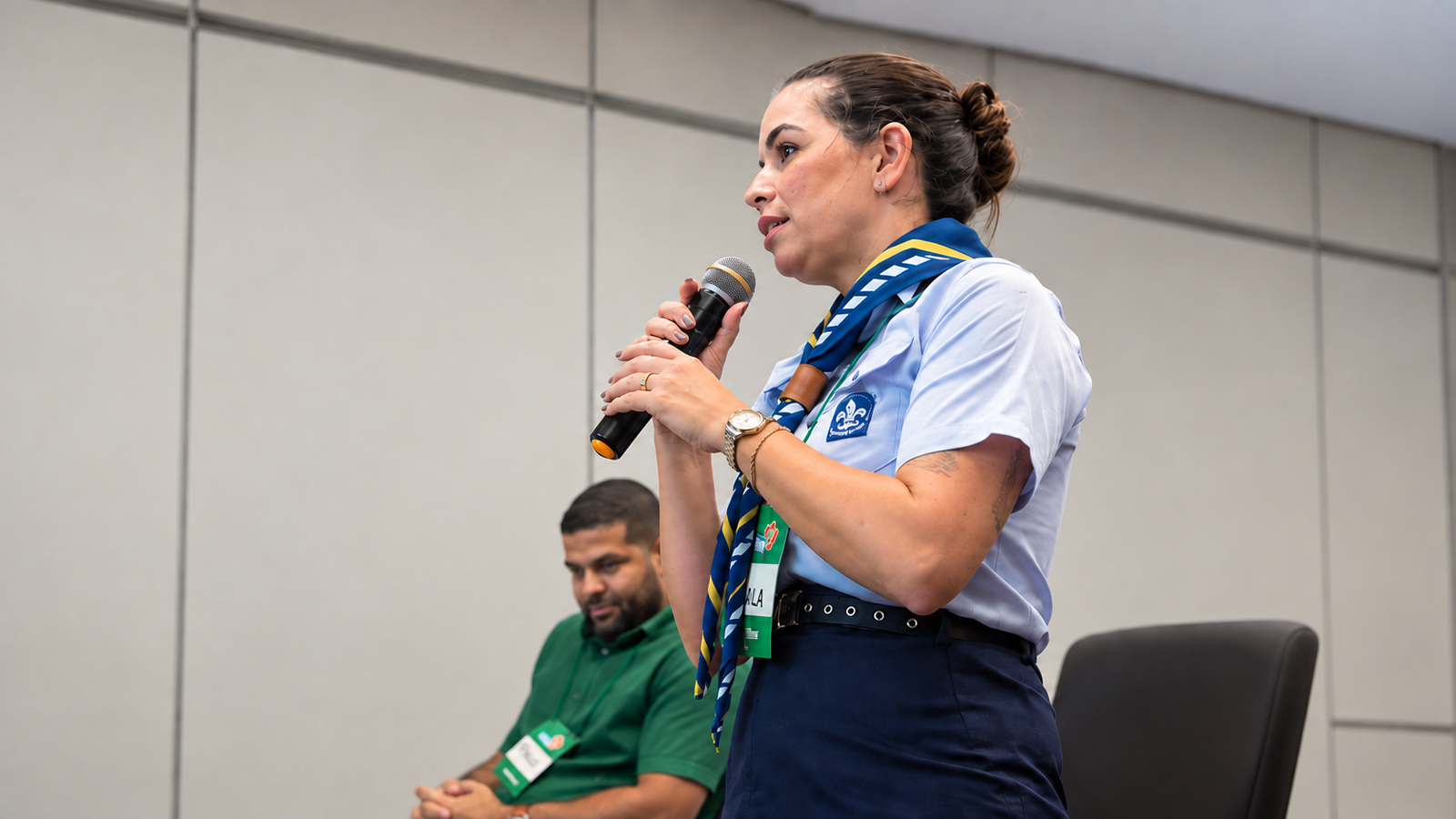 Ana Carla Santos Costa durante sua fala no Encontro Estadual do Juventude Solidária, com o voluntário Thiago Lima Silva ao fundo.